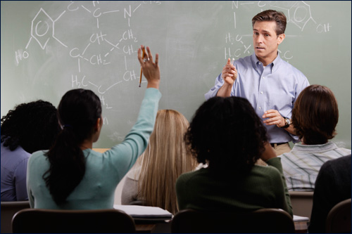 A male teacher answering questions in a classroom.